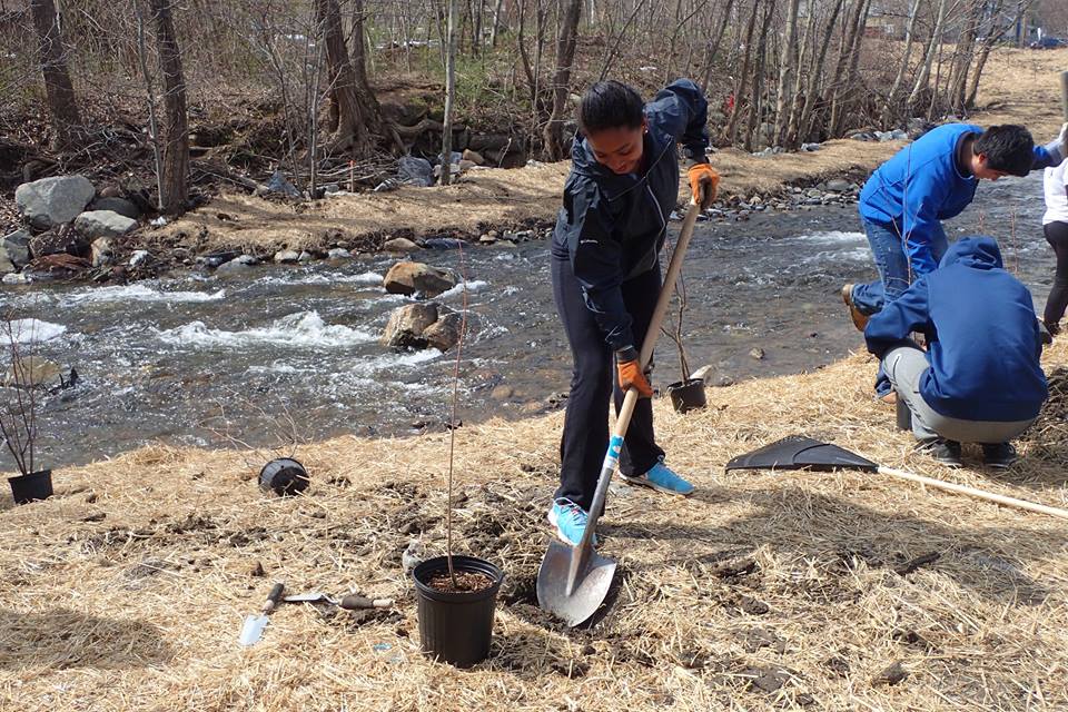 Woman with shovel on bank of flowing river.